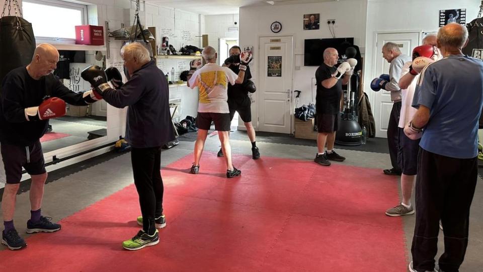 A group of older men do boxing exercises together