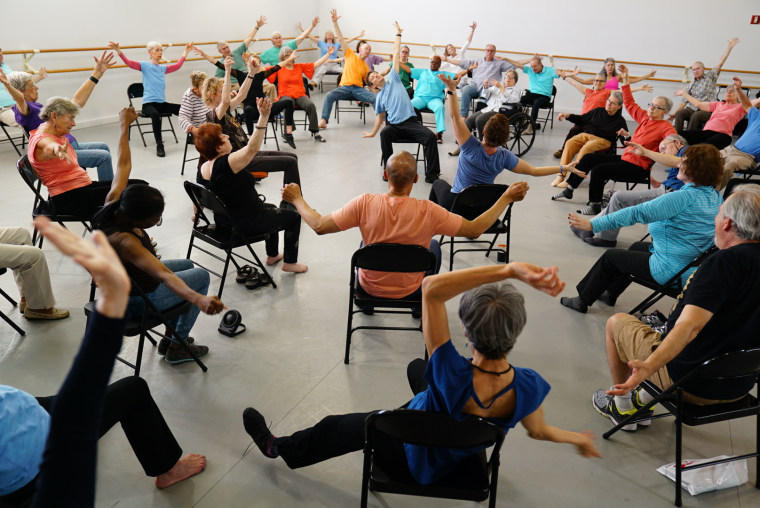 Patients stretch and exercise in a large group.