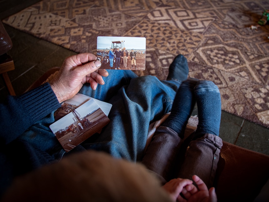 An overhead shot of an older man showing a child a photograph. The child's socked feet stick out over the couch