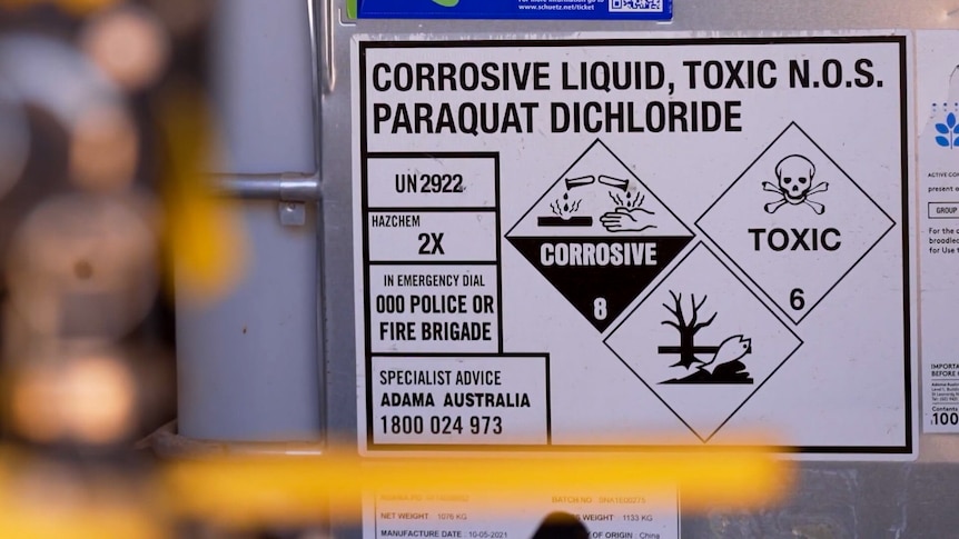 A label on a plastic tub reads CORROSIVE LIQUID, TOXIC N.O.S. PARAQUAT DICHLORIDE