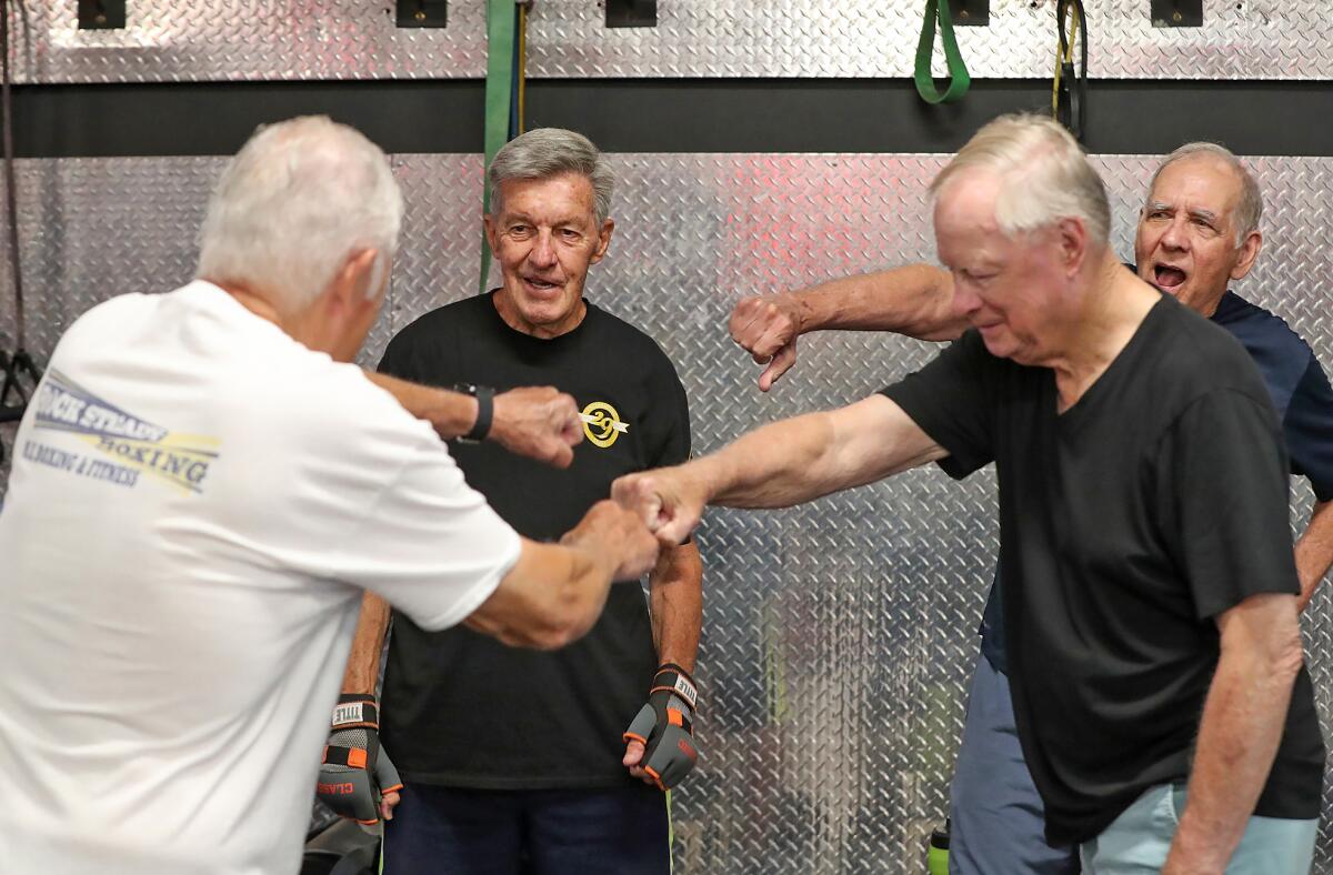 Donna Clervi's clients, "Parkinson's Fighters," high-five with fists, including Pete Mayder, far left, in Irvine on Tuesday.