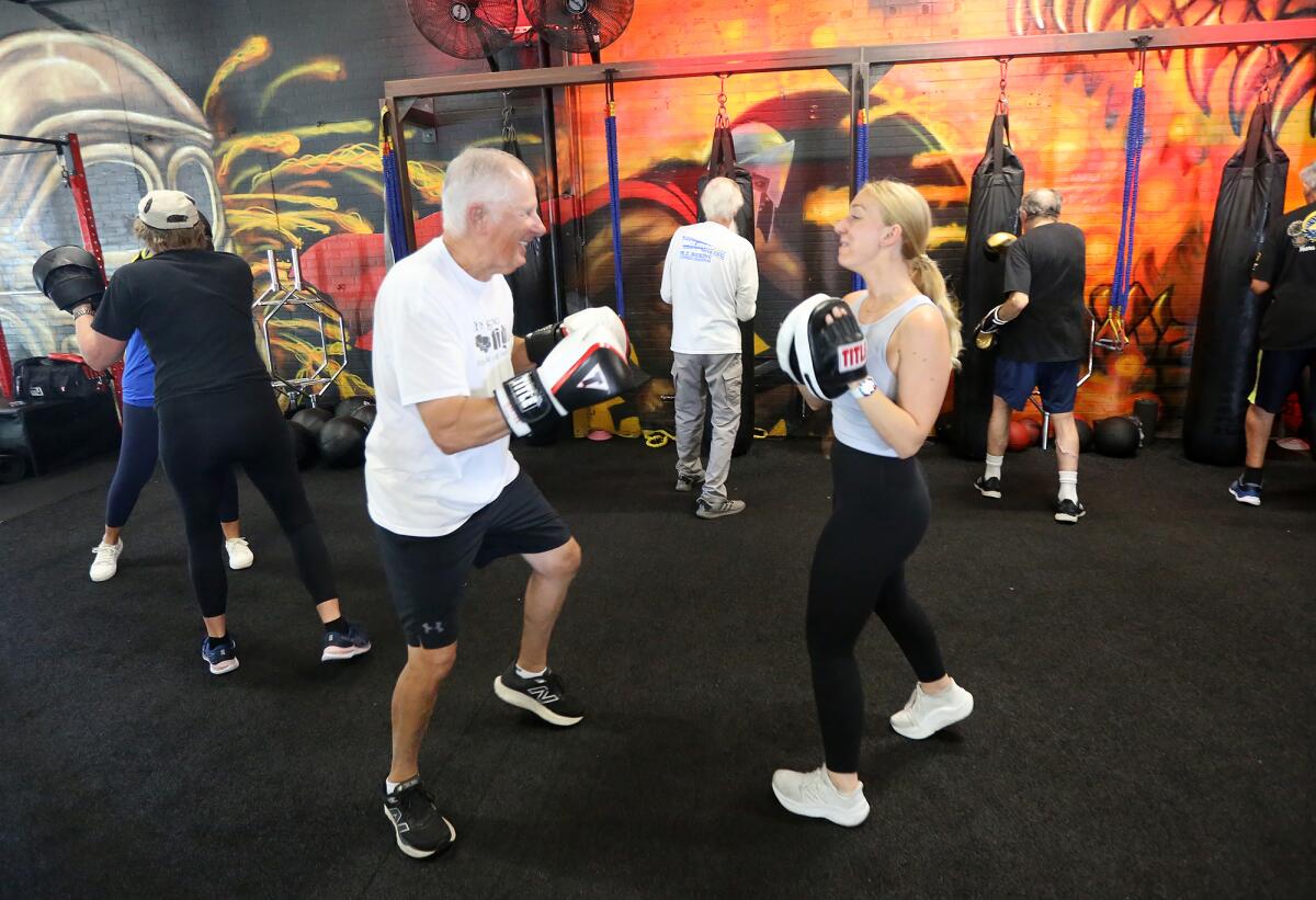 Client Mike Fulmis shares a laugh with speech pathologist Rene Lavelle, left, during a boxing work-out on Tuesday.