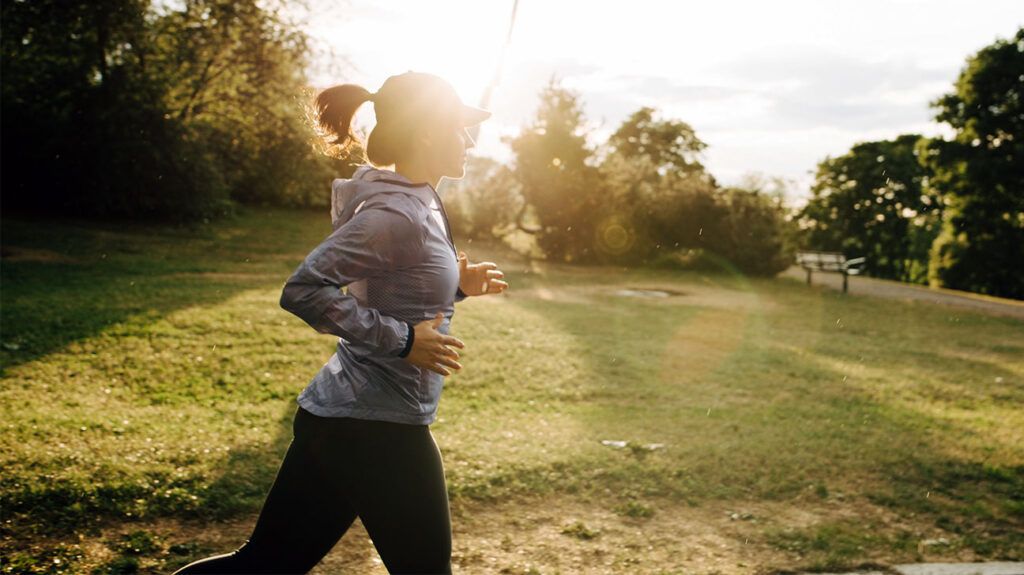 A woman in athletic clothing runs outside at a park