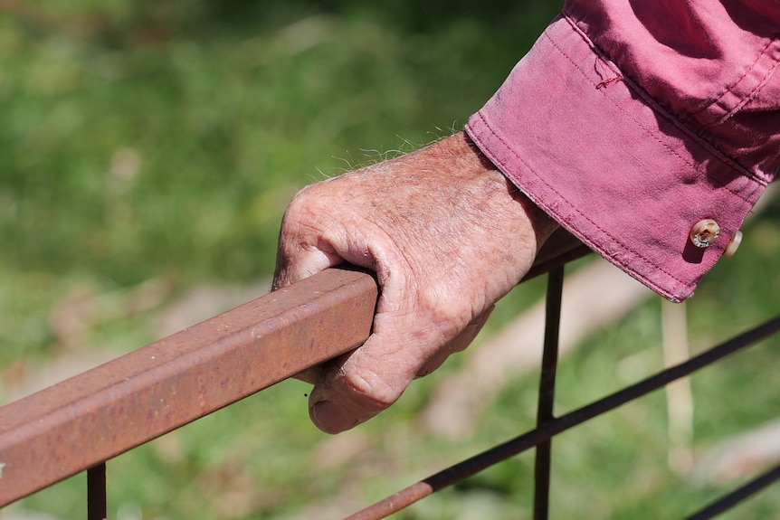 A close up of a man's hand on a fence. 