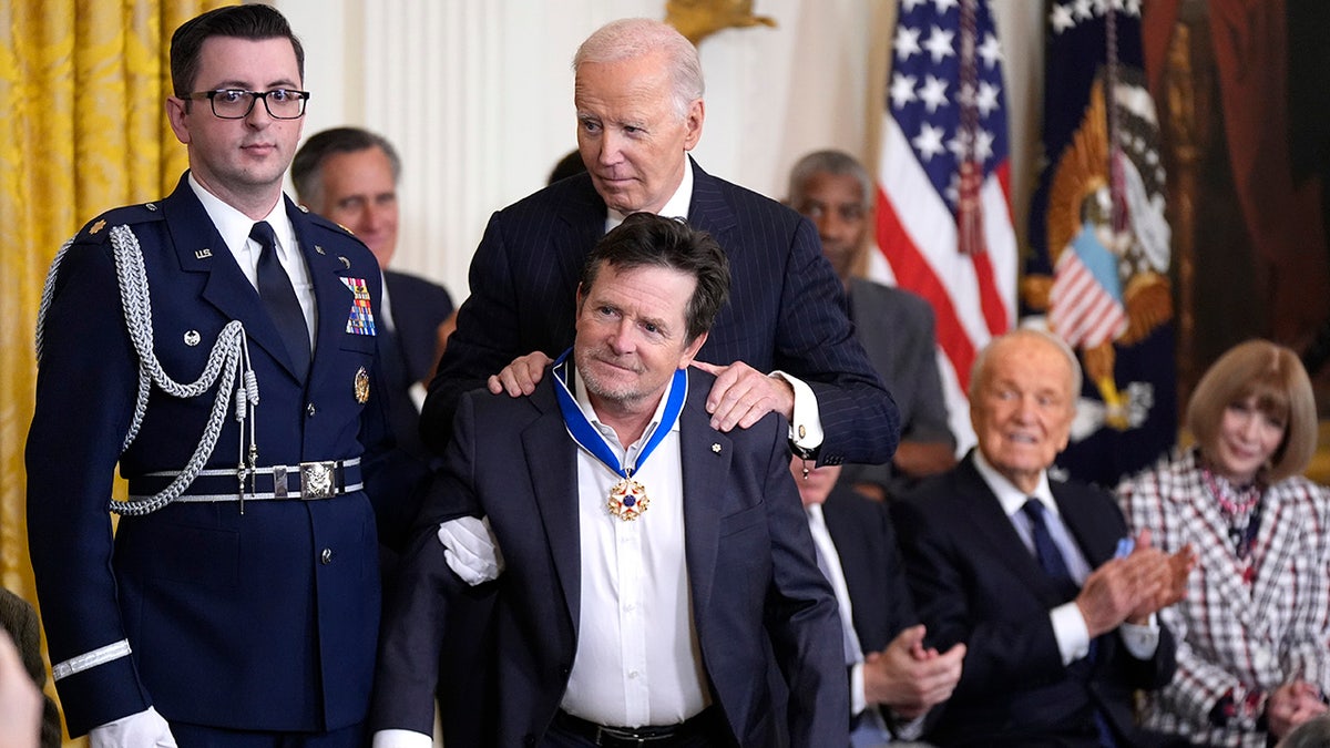 president biden holds michael j fox at his shoulders with the medal of freedom around his neck