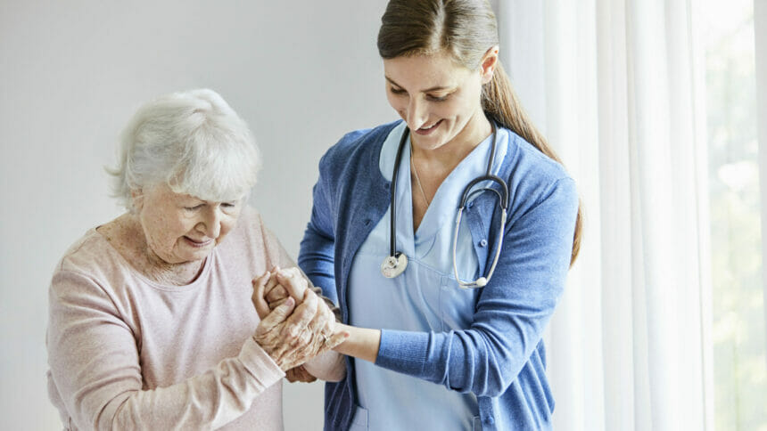 older woman holds nurse's hand