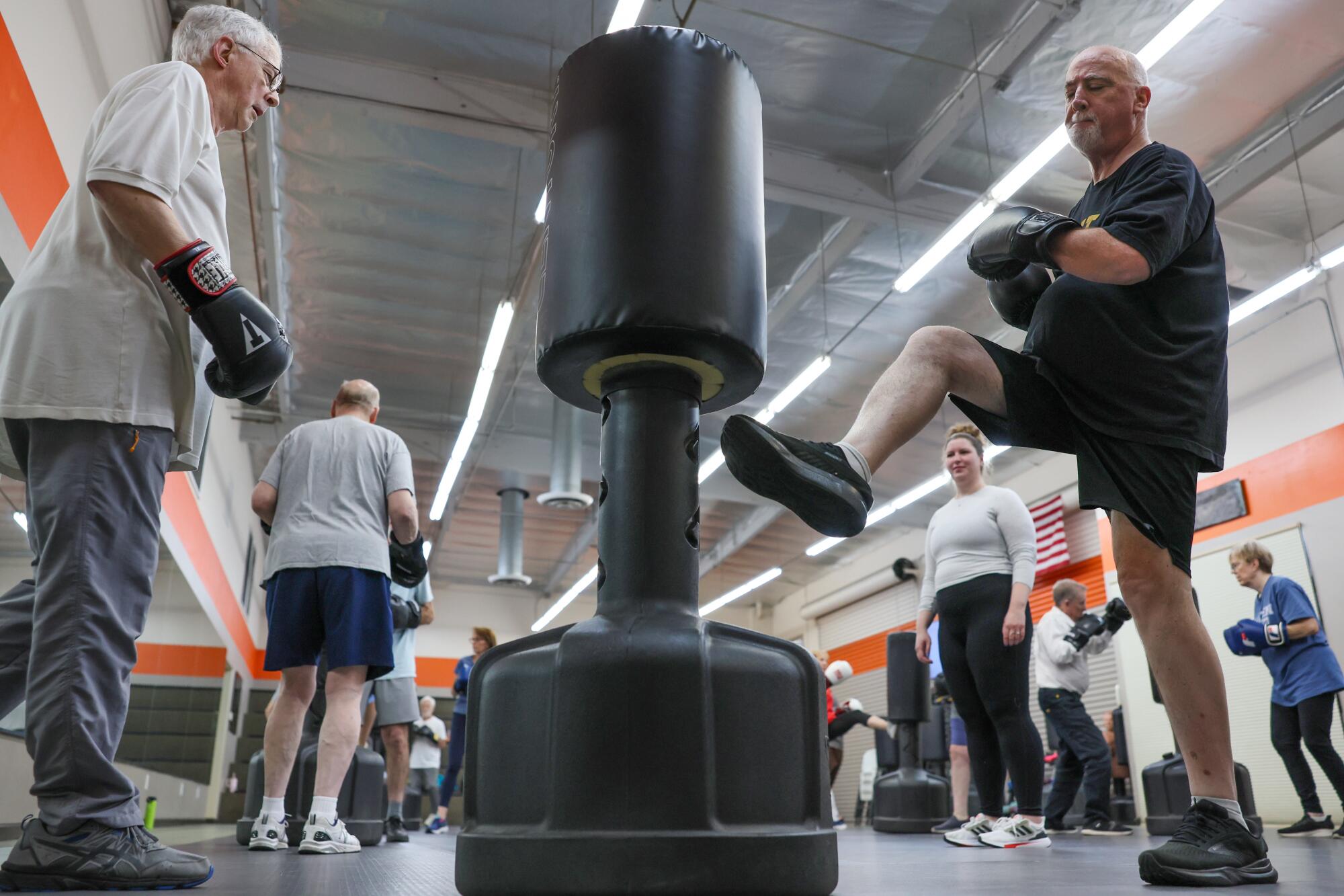 Bill Plaschke and Paul Tellstrom team up hitting a punching bag during a class for people with Parkinson's disease.