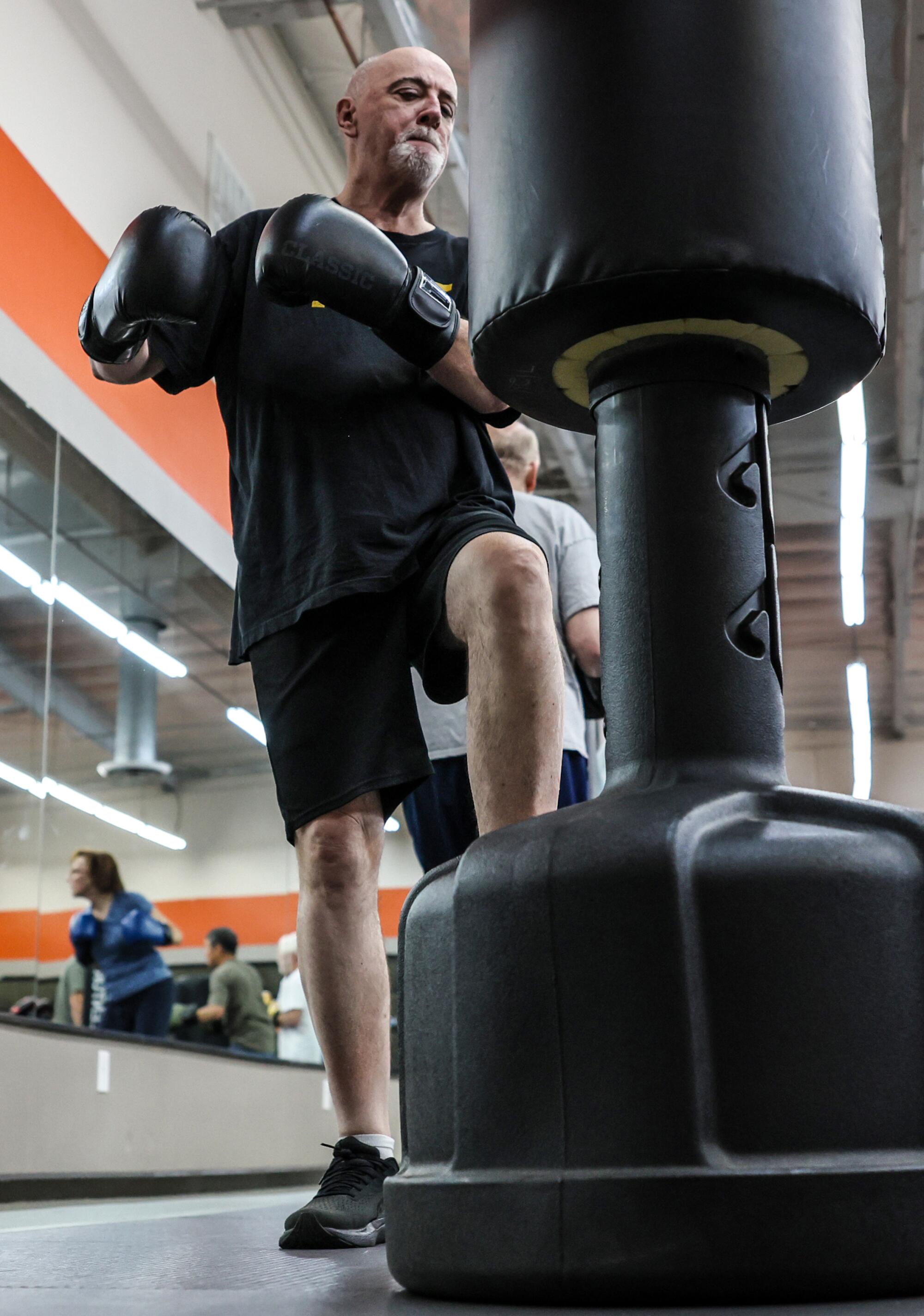 Bill Plaschke steps up and prepares to punch a boxing bag during a class at Kaizen Martial Arts Studio.