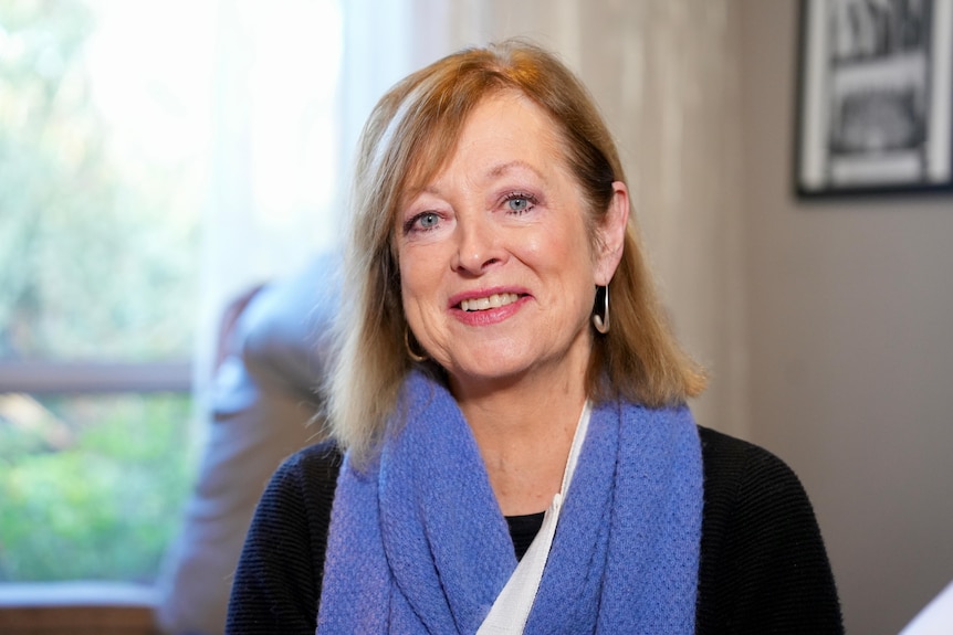 Marcia, an older woman, smiles into the camera.