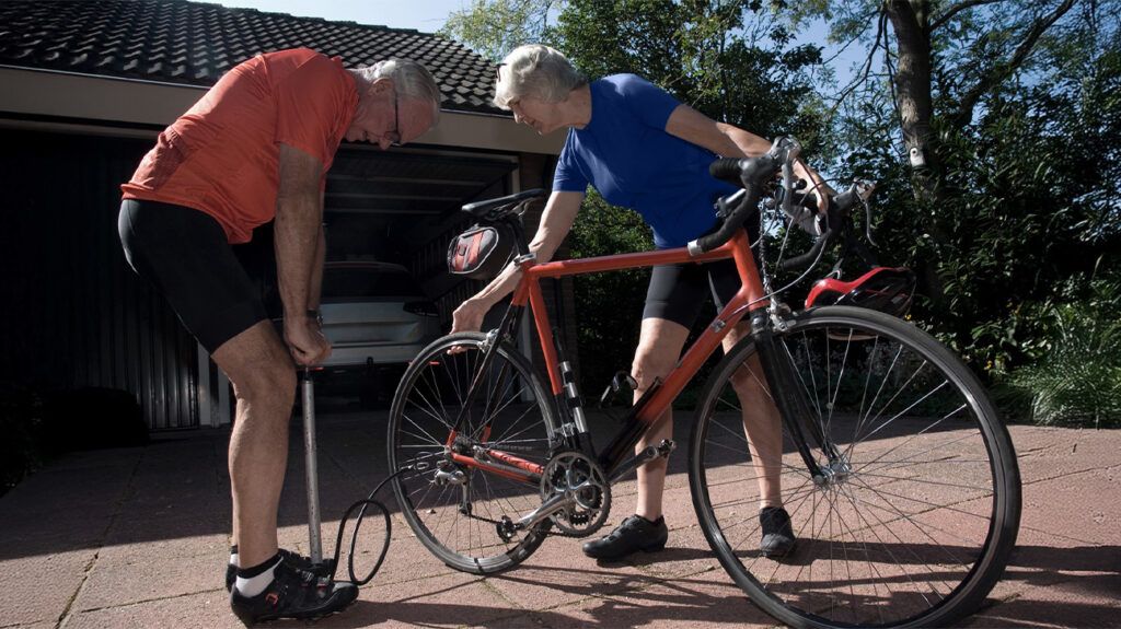 An older adult couple fixing a bicycle outside